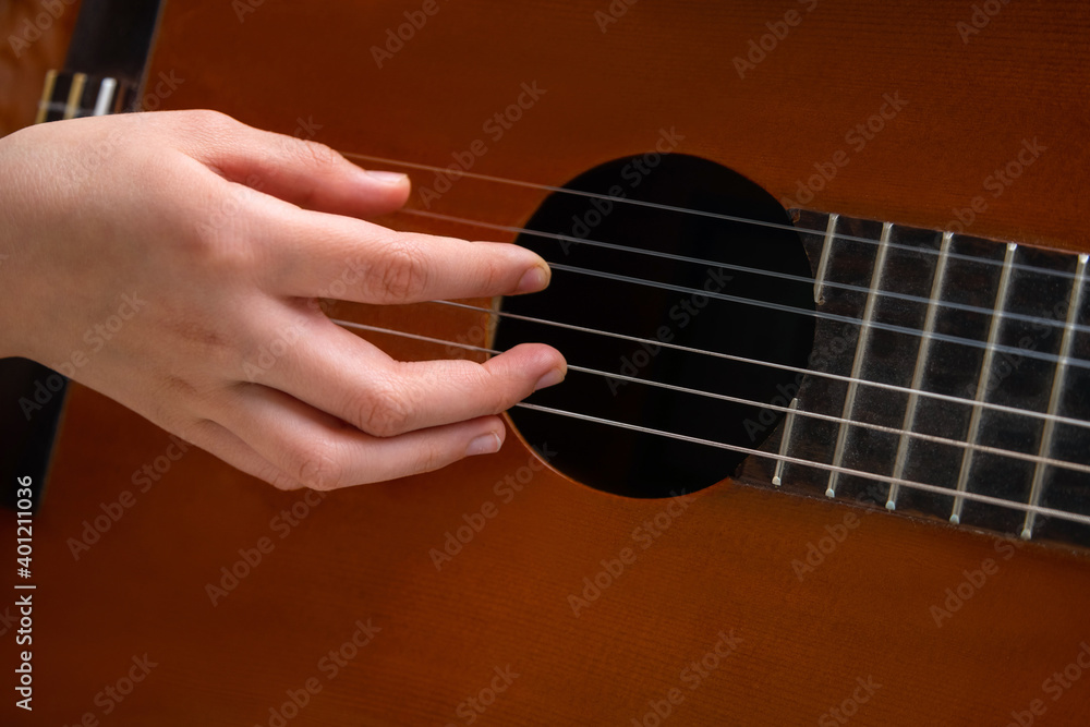 Fototapeta premium Close up of hand playing acoustic guitar. Practicing classic musical instrument. Home school education