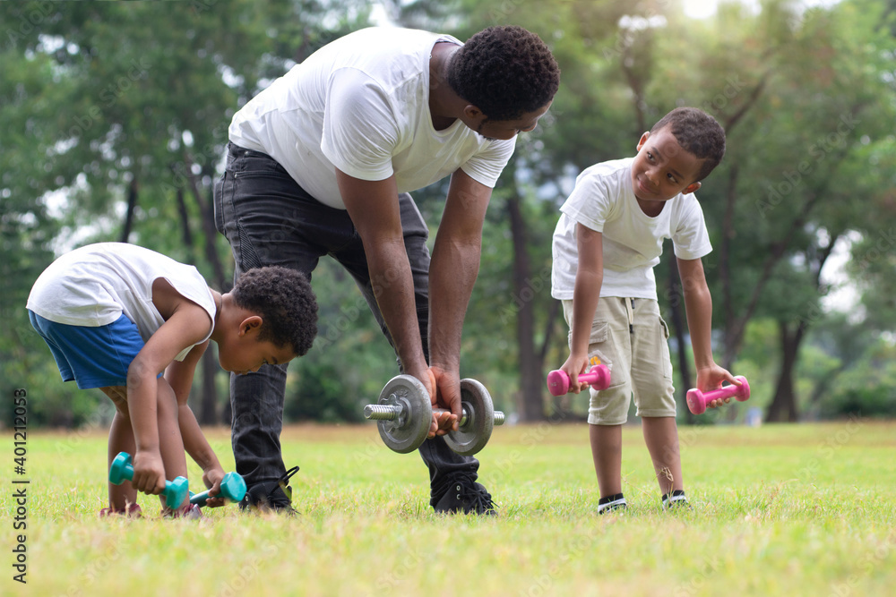 African father and two son exercising with dumbbells in green park, spend time together at outdoor park, Father's day African father and two son exercising with dumbbells in green park, spend time together at outdoor park, Father's day