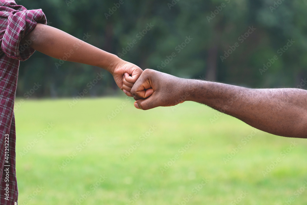 African child boy bumping fists with his father at park, man and child giving fist bumping African child boy bumping fists with his father at park, man and child giving fist bumping