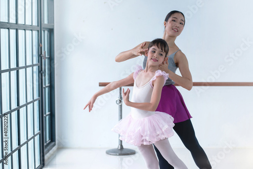 Little ballerina dancing with ballet teacher in dance studio, girl is studying ballet
