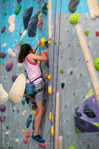 Sporty teen girl climbing artificial boulder on climbing gym, girl climbing on practical wall indoor
