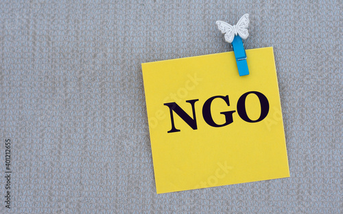 NGO - word on yellow paper with clothespin on gray background