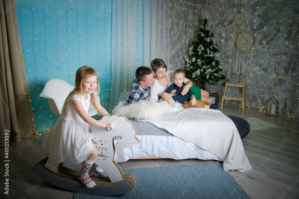 Naklejka premium Family in home interior of Christmas and New Year. parents and children are happy together at christmas. Girl riding a toy horse at home