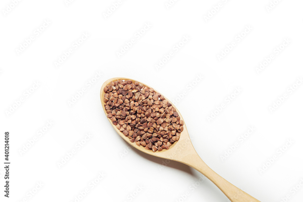 Top view of the wooden spoon filled with uncooked buckwheat isolated on the white background Top view of the wooden spoon filled with uncooked buckwheat isolated on the white background