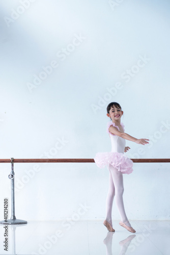 Young girl ballerina dancer in a pink tutu skirt practicing in ballet studio