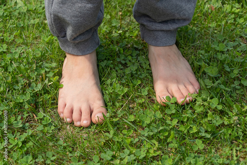 The child standing barefoot on the green grass, feet closeup. Healthy childhood.