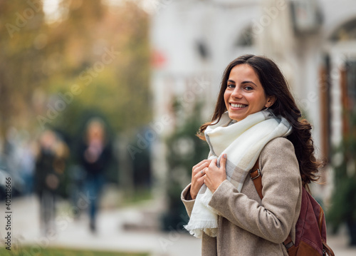 Young lady, wearing coat and scarf, having backpack. © bnenin