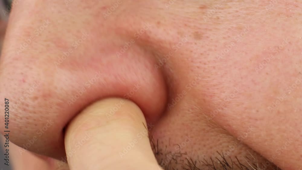 man clean up or picks his right nostril, scratches his itchy nose, loss of smell, close-up side view man clean up or picks his right nostril, scratches his itchy nose, loss of smell, close-up side view
