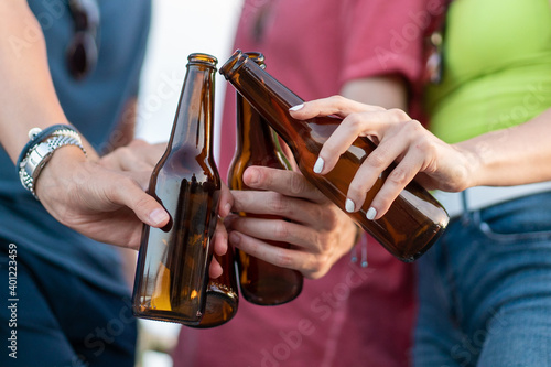 Closeup of person toasting with beer bottles