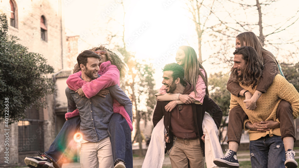 Group of multiracial group of young people walking playing piggyback together. Friendship concept with interracial students having fun outdoors.