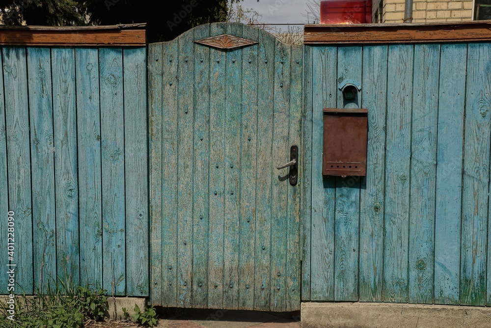 closed blue wooden door and part of a rural fence with a brown letterbox outside