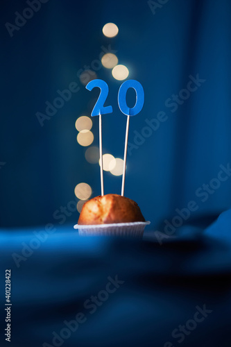 Birthday cake or muffin with number twenty (20) and lights on the blue background. Birthday or anniversary concept photo