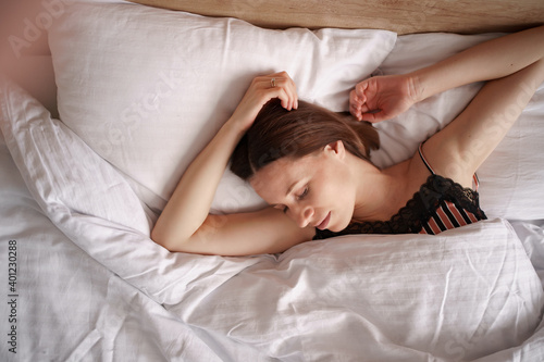 Caucasian woman sleeping in bed. Lady enjoys fresh soft bedding linen and mattress in bedroom