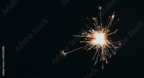 New Year's Eve celebration with a sparkler. Isolated on black background, with copyspace.