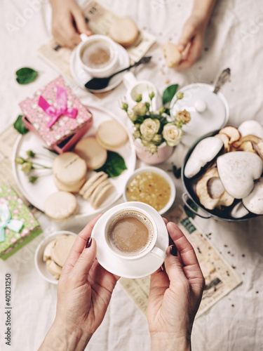 Graceful female hands hold a white cup with cappuccino. Food still life in french style. Toning. Vertical shot