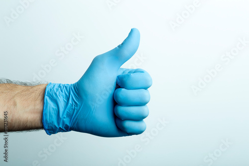«Like» in a medical glove. Doctor's hand in a blue medical glove on a light background.