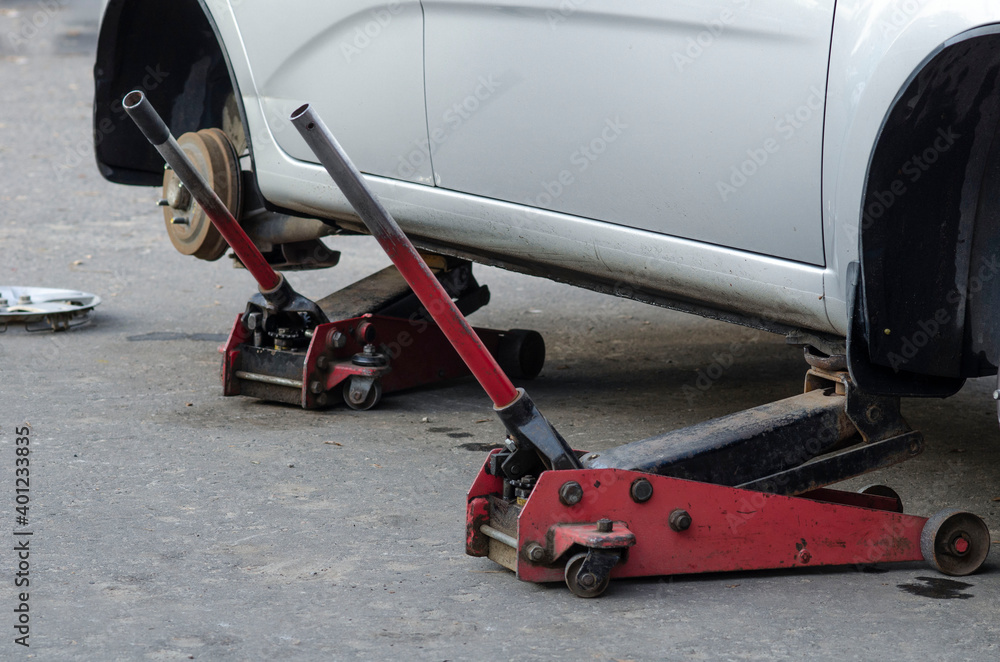 Mechanic screwing or unscrewing changing car wheel by wrench mechanic at work changing a wheel on a car Mechanic screwing or unscrewing changing car wheel by wrench mechanic at work changing a wheel on a car