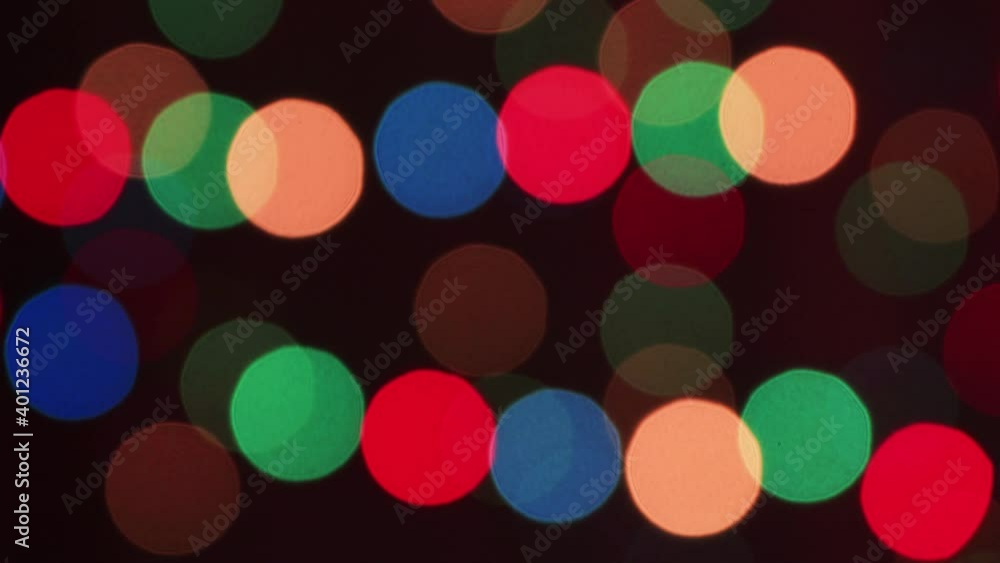 New Year's colored lights in defocus flash in the dark at night. The green beam is moving. Close-up colored circles sway festively. Christmas abstract background. 4K. New Year's colored lights in defocus flash in the dark at night. The green beam is moving. Close-up colored circles sway festively. Christmas abstract background. 4K.