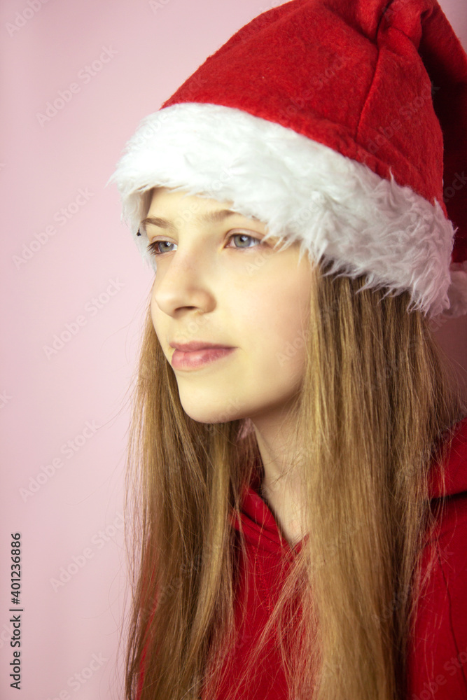 Smiling beautiful girl with long blonde hair in fluffy Santa Claus hat on a pink background. Smiling beautiful girl with long blonde hair in fluffy Santa Claus hat on a pink background.