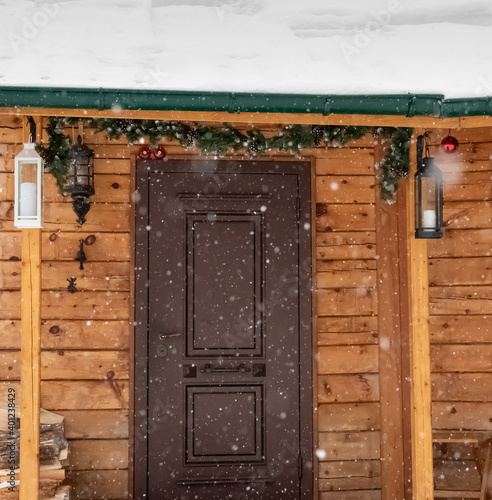 Fototapeta Naklejka Na Ścianę i Meble -  Door to a house with Christmas decorations during a snowfall