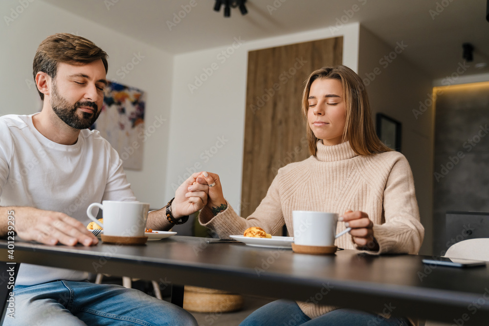 Couple praying while sitting at the dining table Couple praying while sitting at the dining table