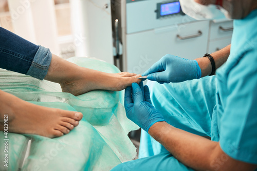 Beautiful woman visiting podiatrist and receiving professional treatment on the legs in medical center