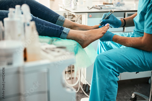 Professional doctor podiatrist doing medical pedicure procedure in the cabinet photo