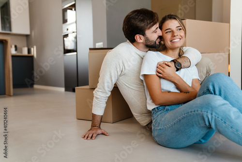 Beautiful couple hugging while sitting with boxes in new apartment © Drobot Dean