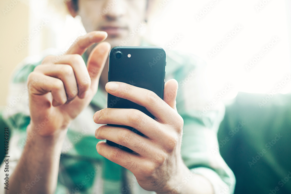 Young man on a couch at home, using mobile phone