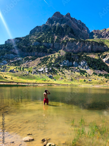 Guy taking a bath in a lake surrounded by mountains.