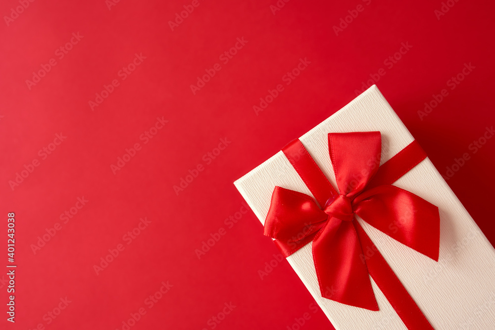 White present with red ribbon on the bright red background White present with red ribbon on the bright red background