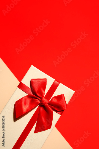 White present with red ribbon on the bright red background . Festive backdrop for holidays: Birthday, Valentines day, Christmas, New Year.