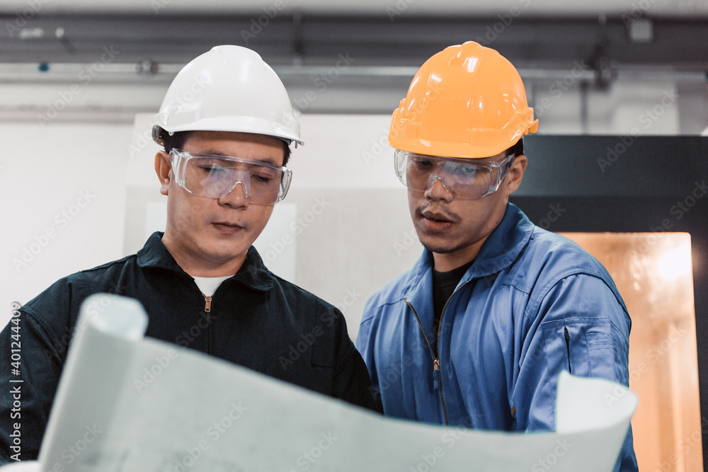 Asian male engineer worker discuss about factory project on planning paper with foreman at industrial plant industry. teamwork corporate people concept Asian male engineer worker discuss about factory project on planning paper with foreman at industrial plant industry. teamwork corporate people concept