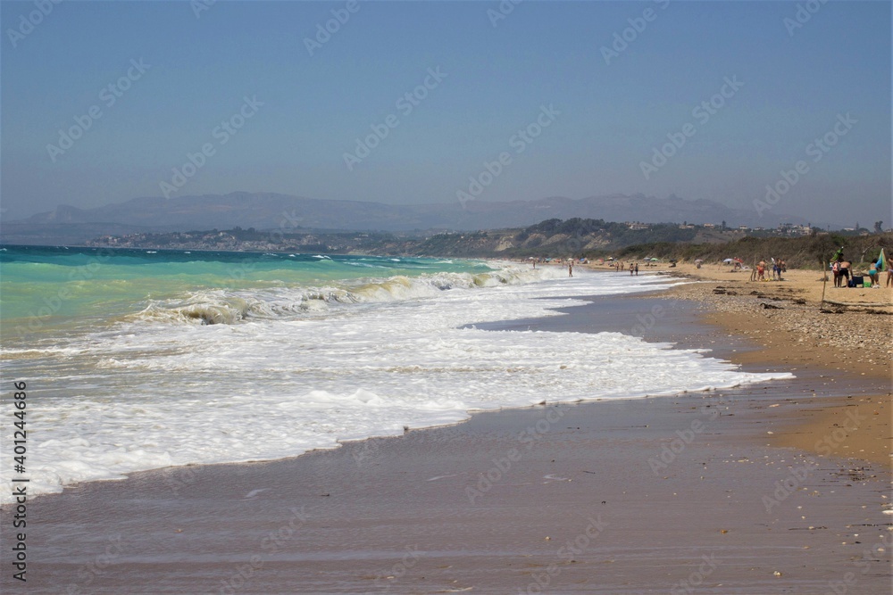evocative image of a sandy beach with a sea of many colors and clear skies
