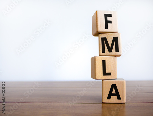 FMLA symbol. Concept words 'FMLA, family medical leave act' on wooden cubes on a beautiful wooden table, white background. Copy space. Medical and FMLA concept. photo