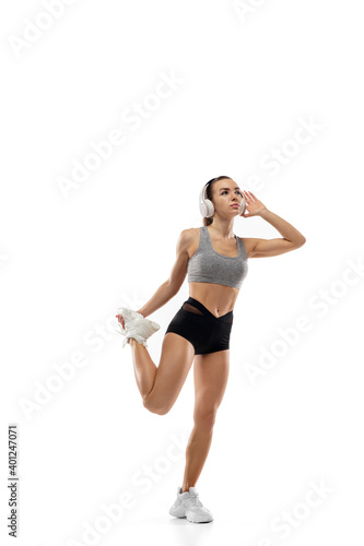 Fototapeta Naklejka Na Ścianę i Meble -  Stretching. Caucasian professional female athlete, runner training isolated on white studio background. Muscular, sportive woman. Concept of action, motion, youth, healthy lifestyle. Copyspace for ad.