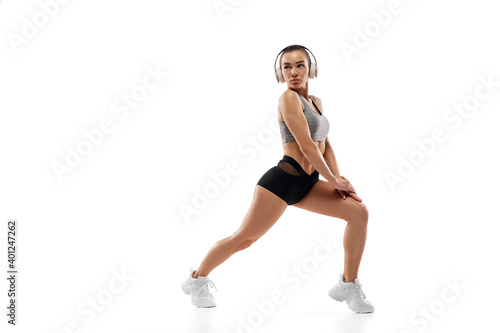 Sits up. Caucasian professional female athlete, runner training isolated on white studio background. Muscular, sportive woman. Concept of action, motion, youth, healthy lifestyle. Copyspace for ad.
