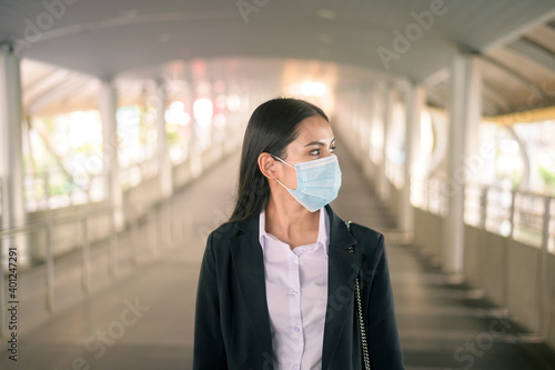 Young business woman with face mask is standing on metro platform using smart.