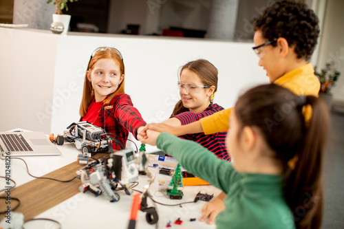 Happy kids programming electric toys and robots at robotics classroom