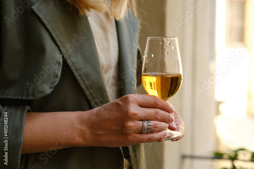 Beautiful girl with a wine glass on the balcony. Drinks white wine and enjoy the moment. A celebration holiday alone. Relaxed lifestyle. Happy woman rest after work. Beautiful European courtyard