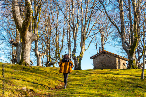 Young girl on the trekking trail in the Oianleku beech forest and the refuge house in the background, in the town of Oiartzun, Gipuzkoa. Basque Country. Spain © unai