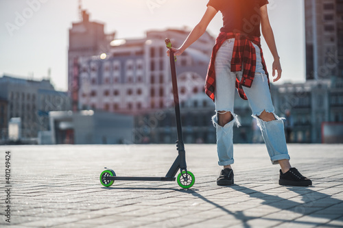 Fotografi young teenager in sneaker on modern extreme stunt kick scooter in city