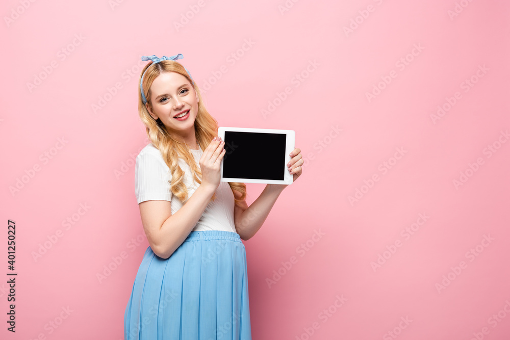 smiling blonde young pregnant woman showing digital tablet on pink background. smiling blonde young pregnant woman showing digital tablet on pink background.