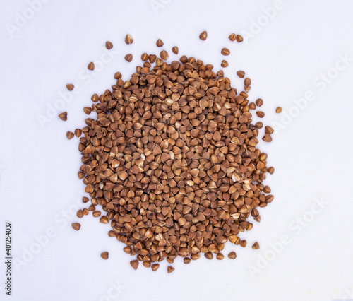 Brown buckwheat heap isolated on white background. Bio nutrition  natural food ingredient. Close up top view. Free space for copy 