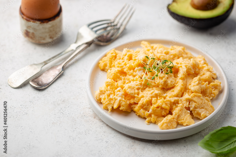 Fresh cooked scrambled eggs in a plate on white background.