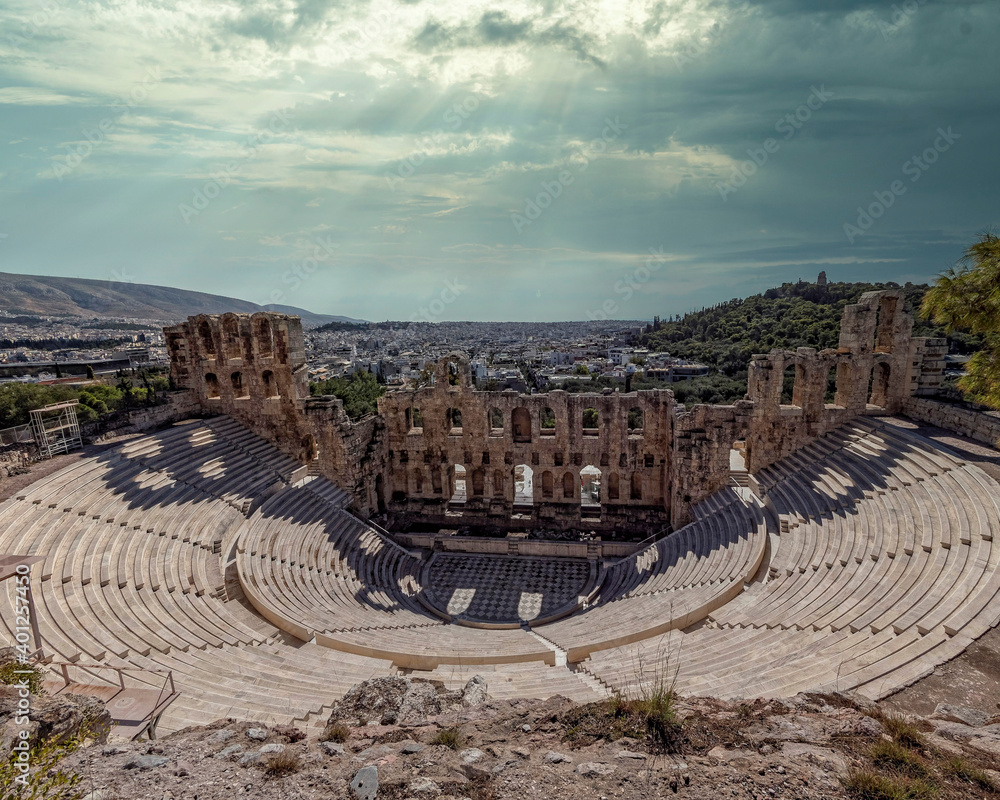 Herodeon ancient open theatre and Athens city panoramic view under dramatic cloudy sky, Greece