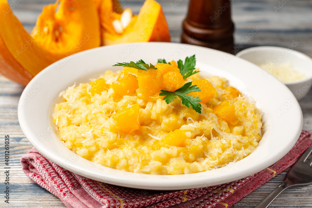 Pumpkin risotto with parmesan cheese and parsley in plate on wooden background