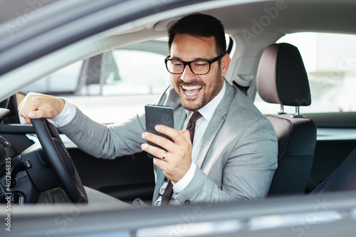 Businessman texting on his mobile phone while driving. © zorandim75