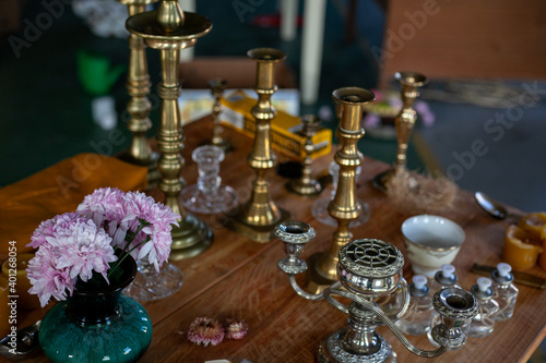 a variety of vintage silver and copper candlesticks and a vase of flowers on a wooden table