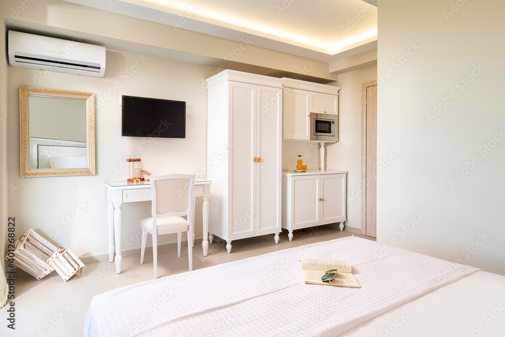 White elegant interior of small studio apartment room with classic style design wooden panel furniture in modern hotel flat.